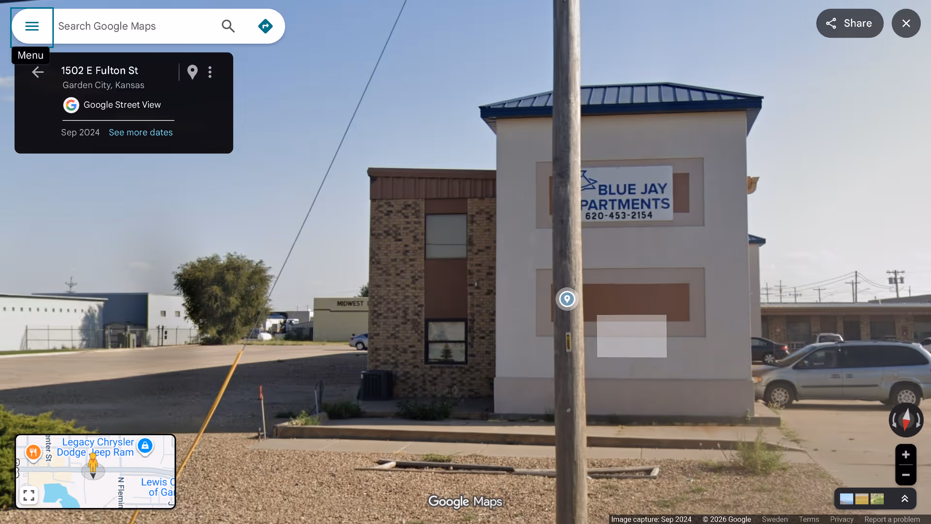 Exterior view of a building with a Blue Jay Apartments sign along the street.