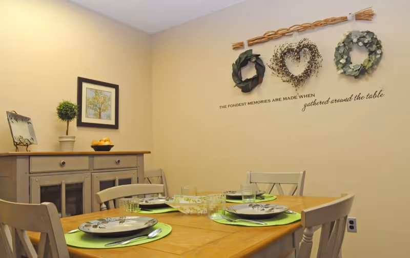 Dining room with a wooden table set for four and wall decorations.