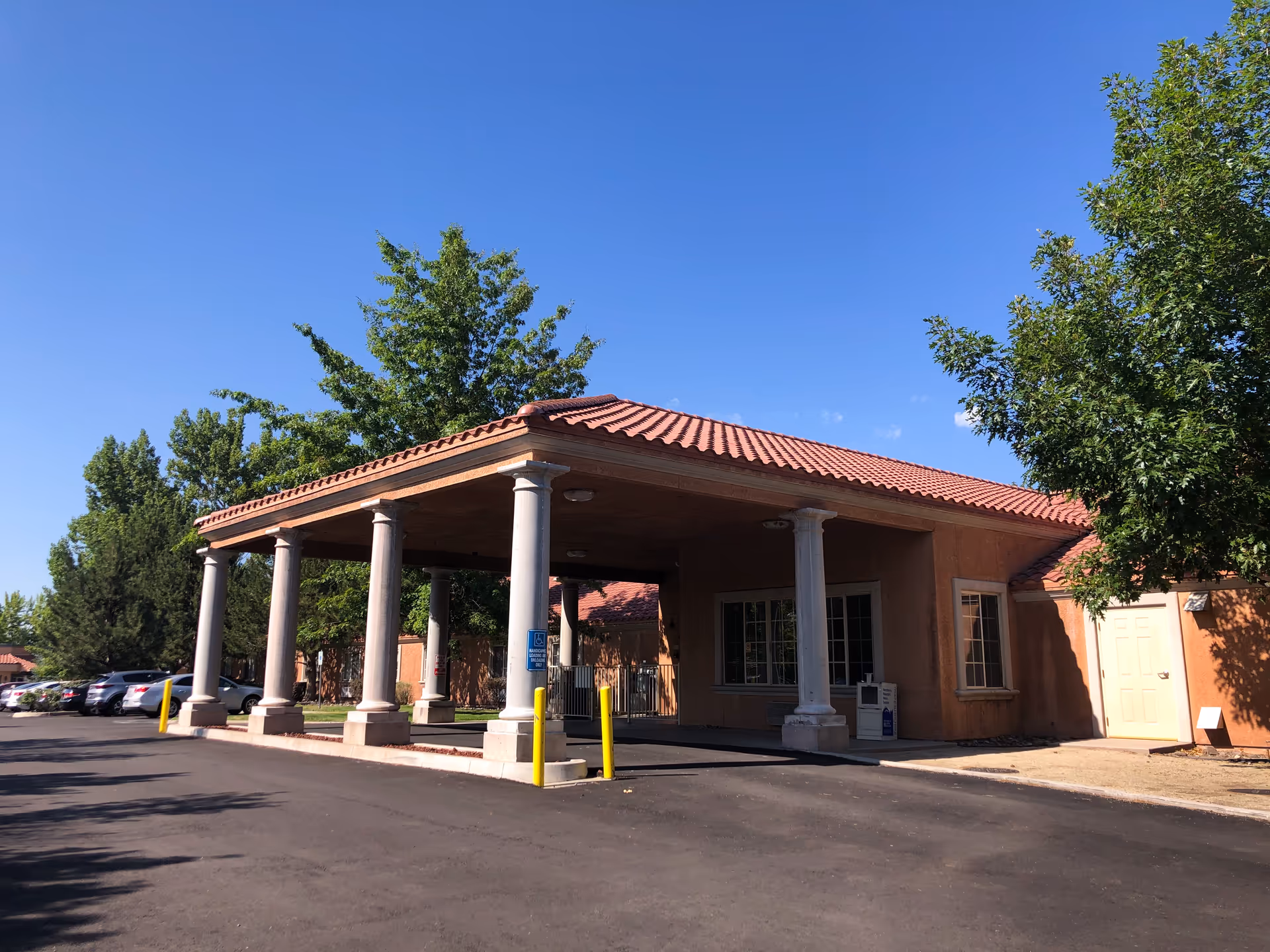 Exterior view of a peach-colored nursing center with a covered entrance and tall columns.