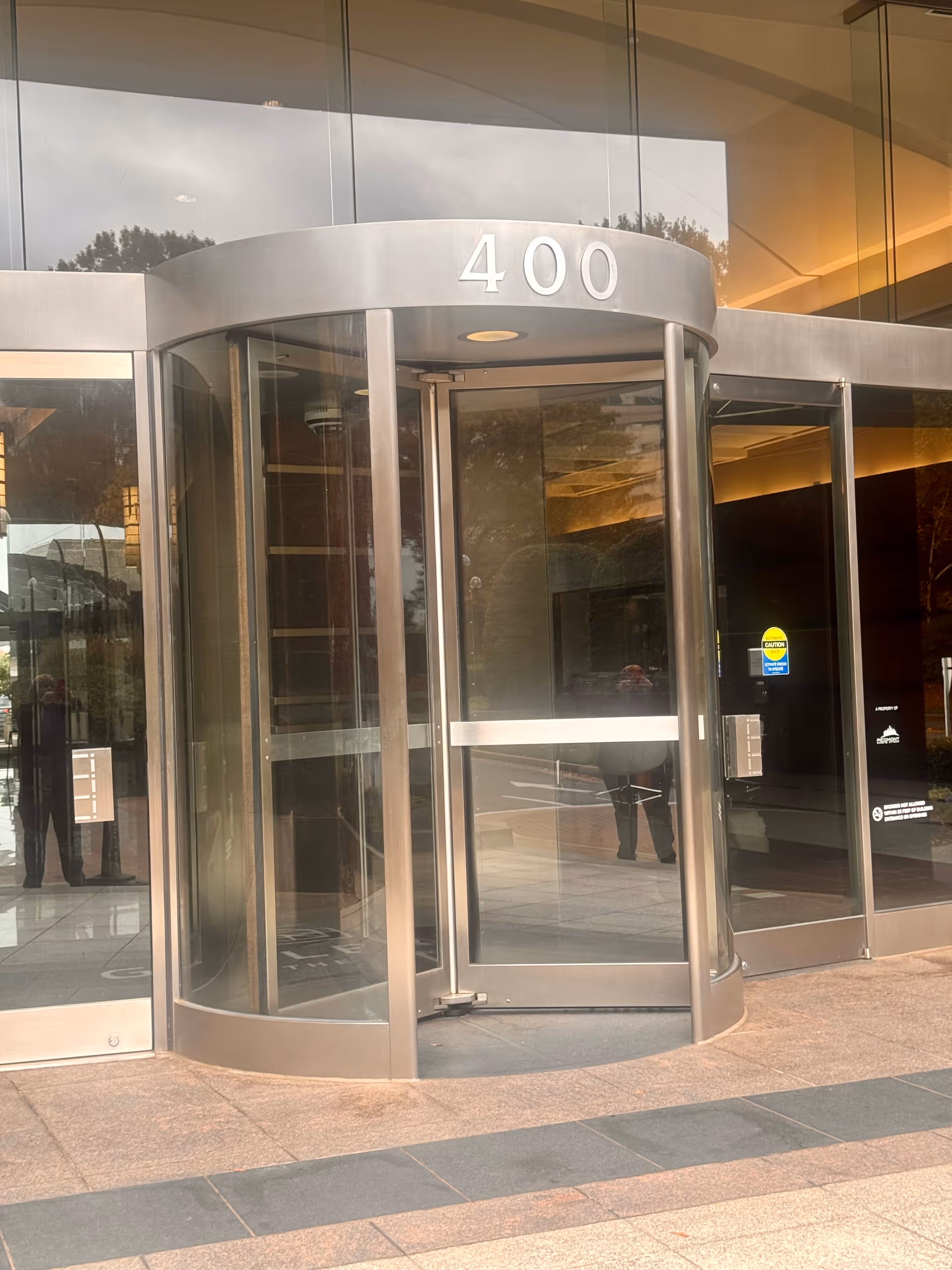 Glass revolving door entrance of a building displaying the number 400.