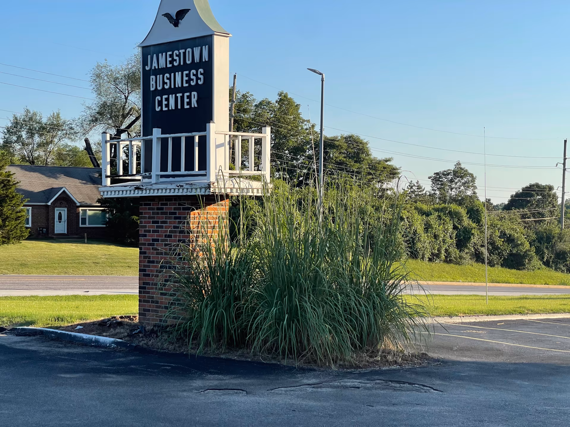 Brick sign tower reading Jamestown Business Center with tall ornamental grasses nearby