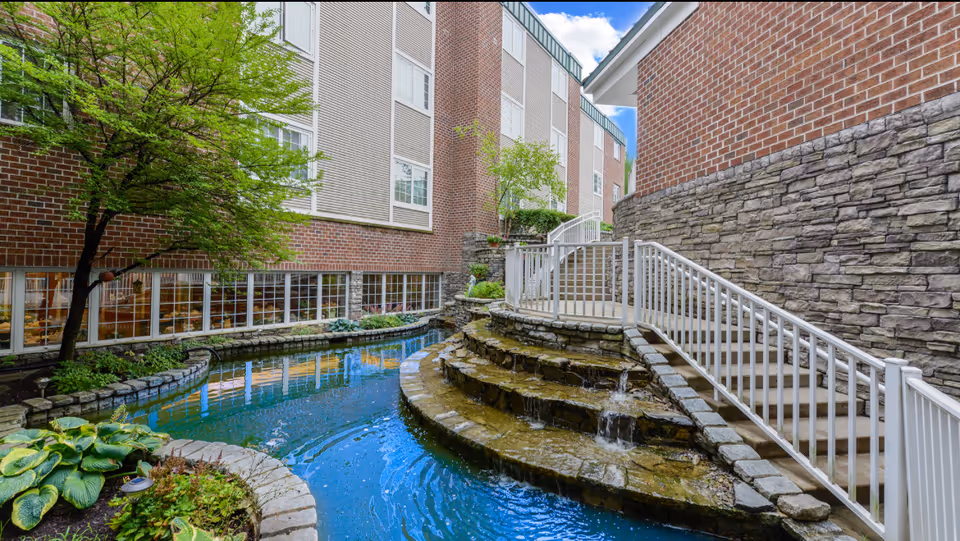 Exterior courtyard at Bethel Health Care Center featuring a tiered stone waterfall and railing.