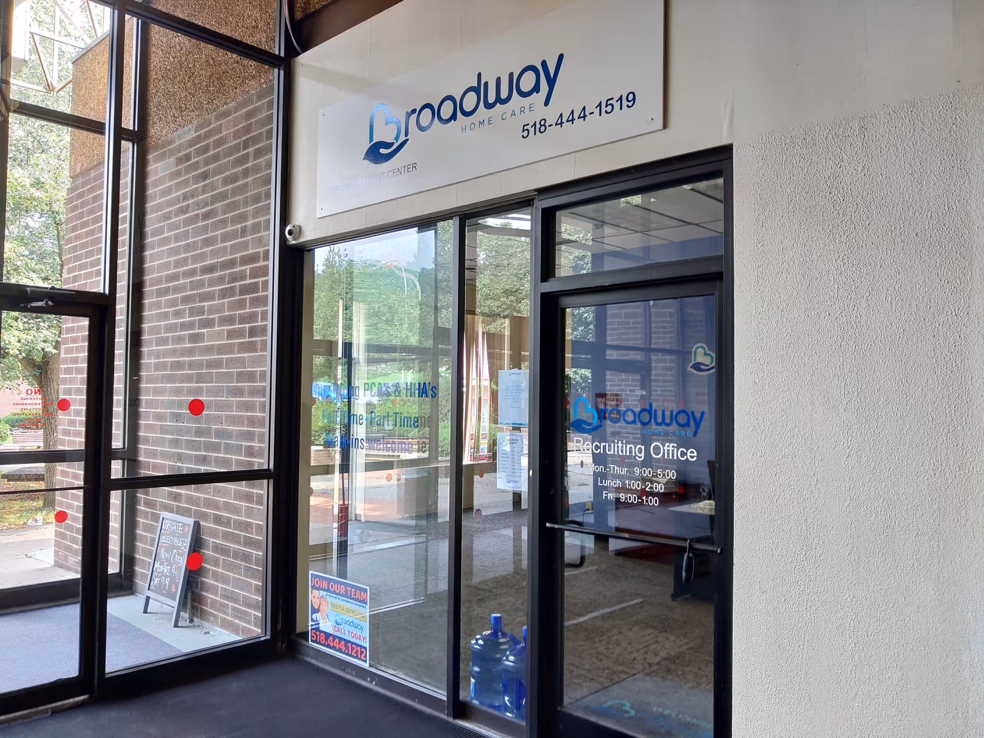 Exterior view of a building entrance with a Broadway Home Care sign and glass doors.