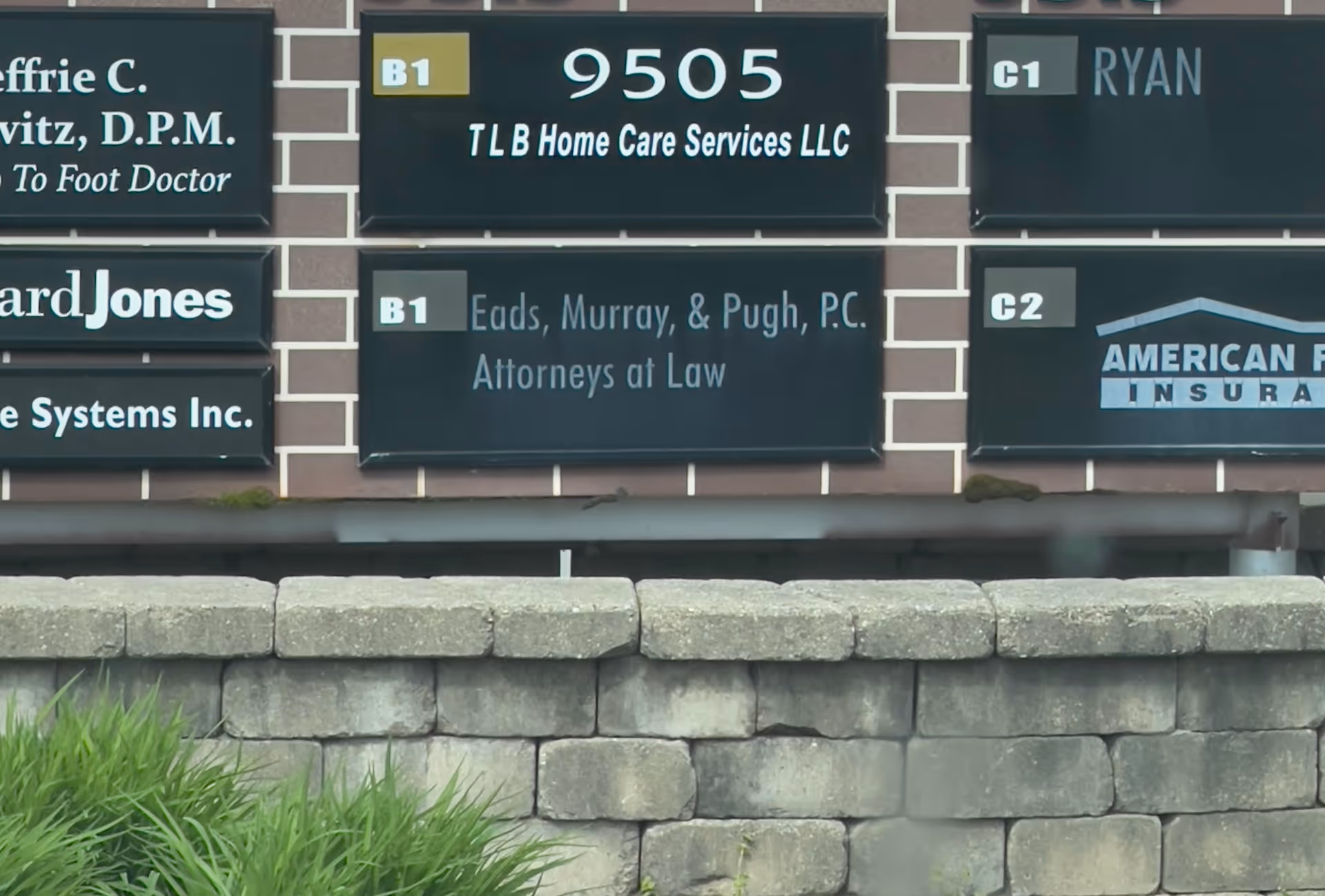 Exterior brick wall with multiple business signs, including TLB Home Care Services LLC at 9505