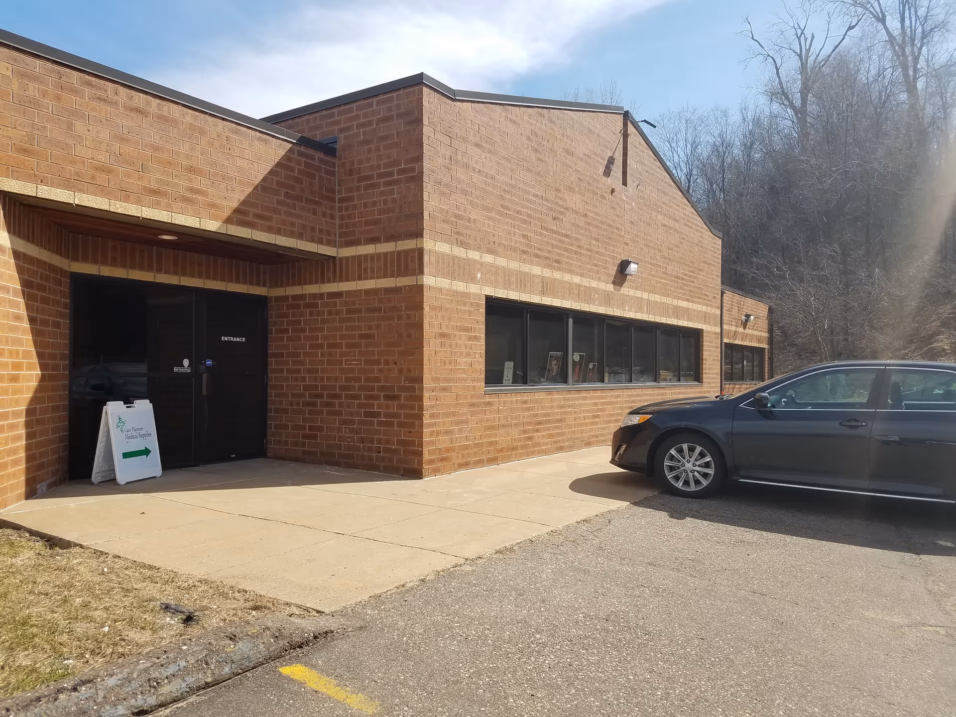 Brick exterior with a front entrance and a parked car nearby.
