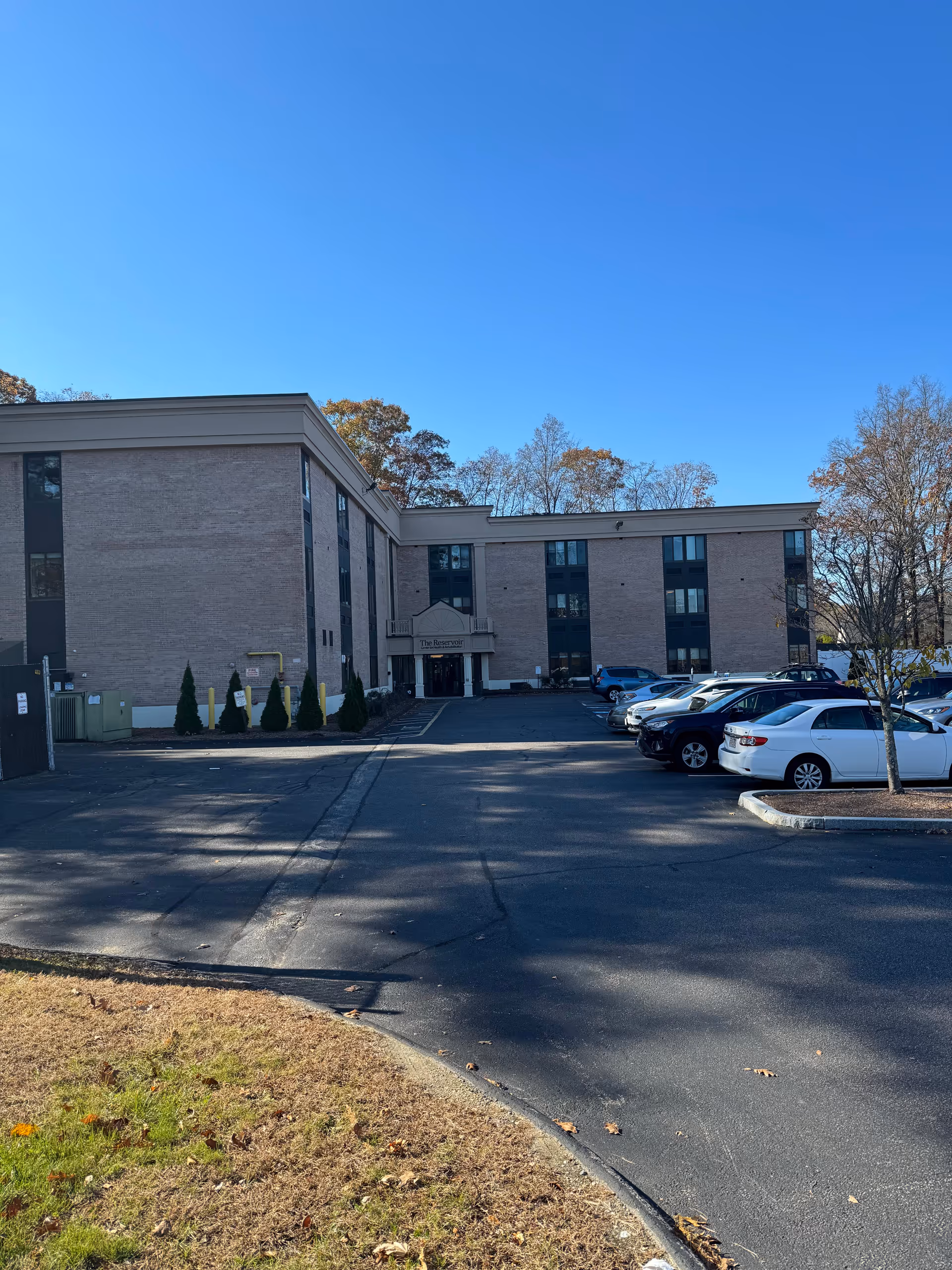 A brick senior living facility with a parking lot and blue sky.