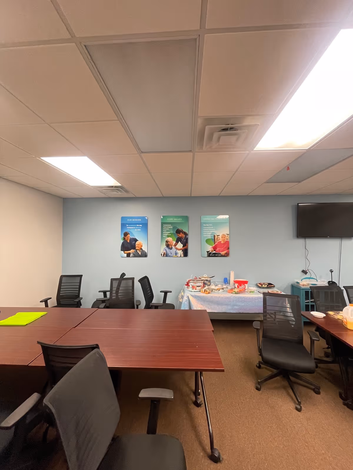 Conference room with tables, chairs, and a snack table against a blue wall.
