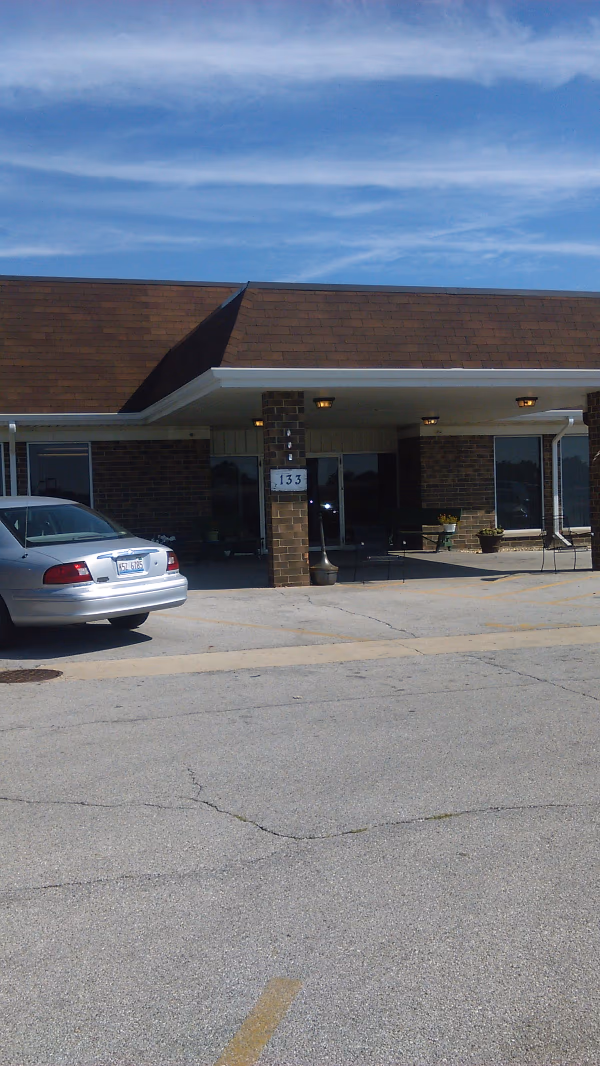 Front exterior view of Bourbonnais Terrace with brick facade, entrance, and parked car.