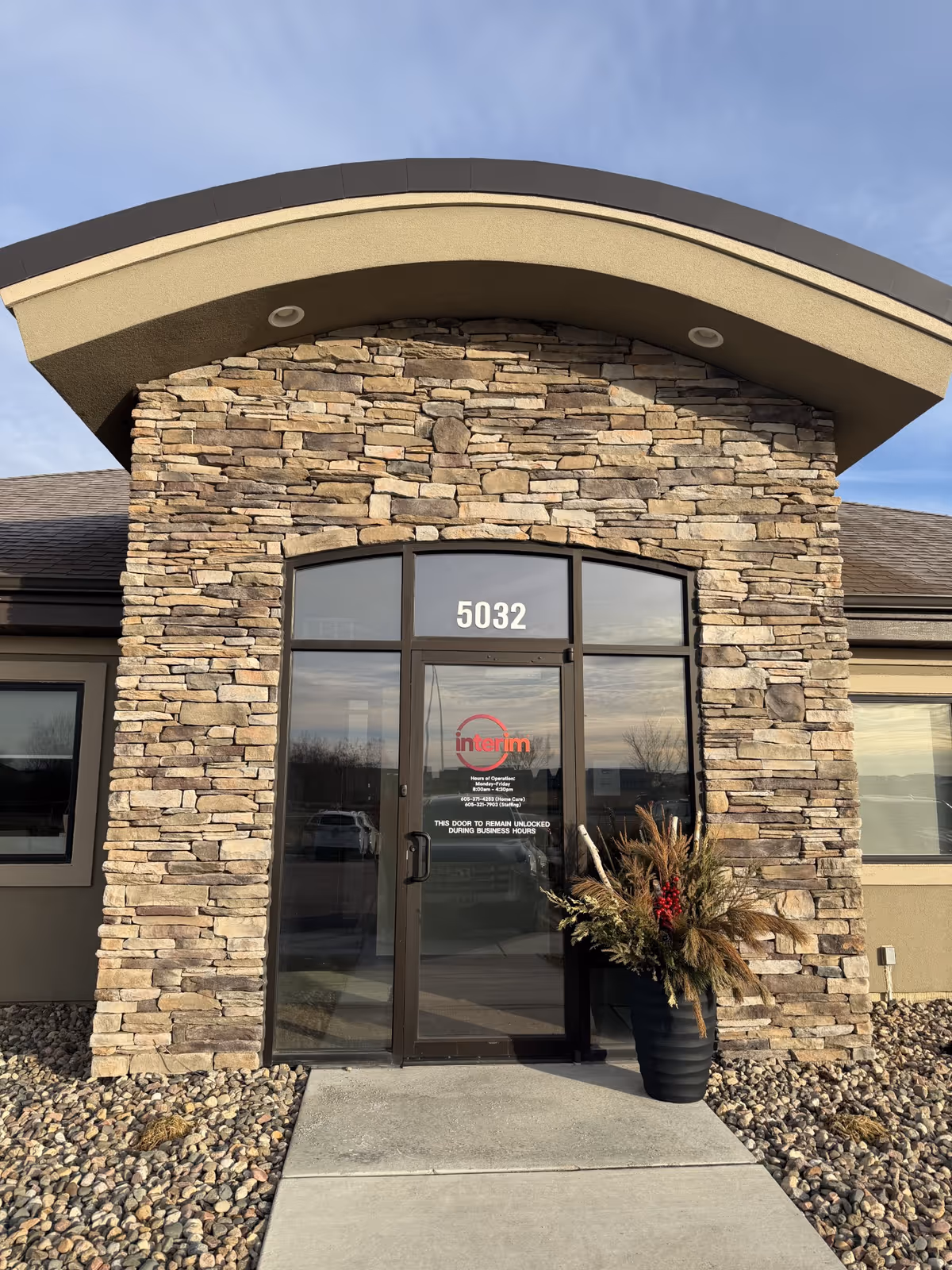 Stone facade entrance of Interim HealthCare with arched glass doors and 5032.