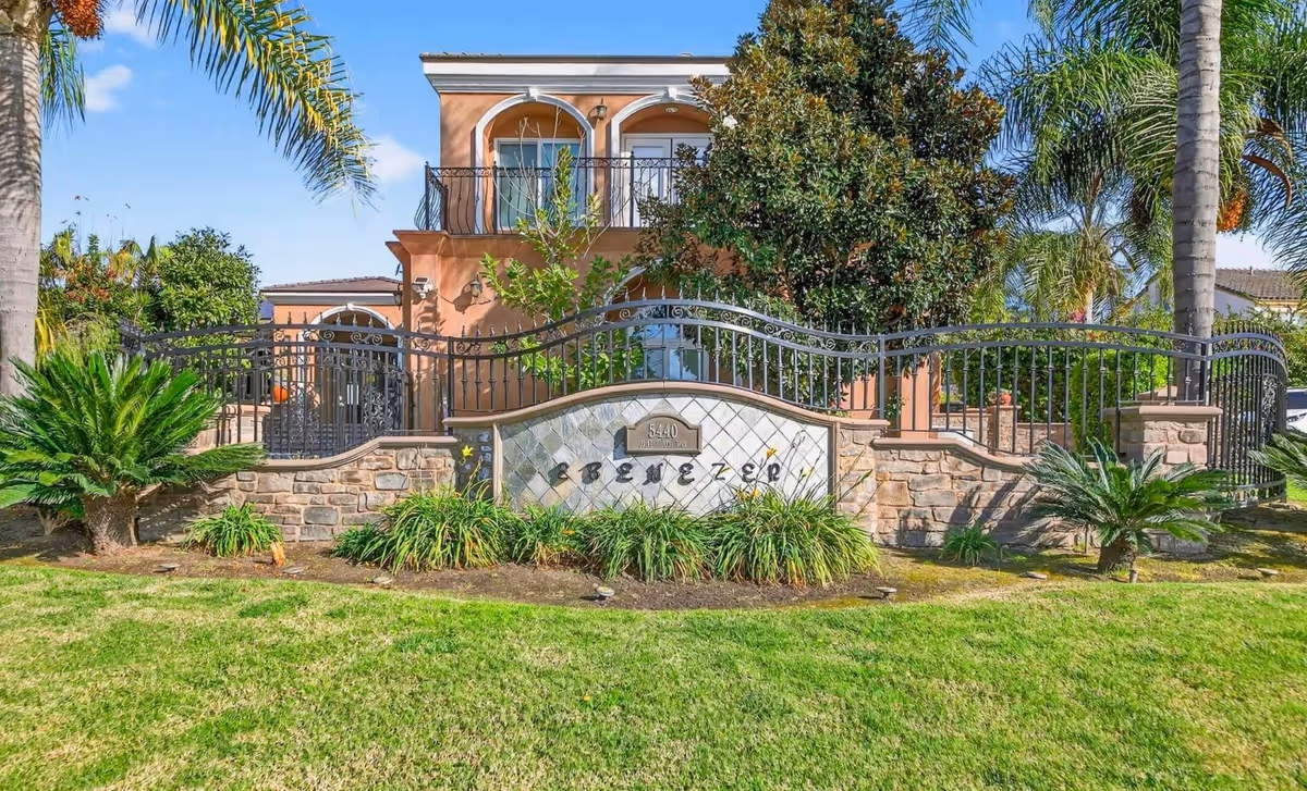 Exterior view of Ebenezer Care Home with stone wall, railing, and lush landscaping.