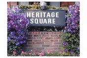 Heritage Square sign on brick wall framed by purple flowers