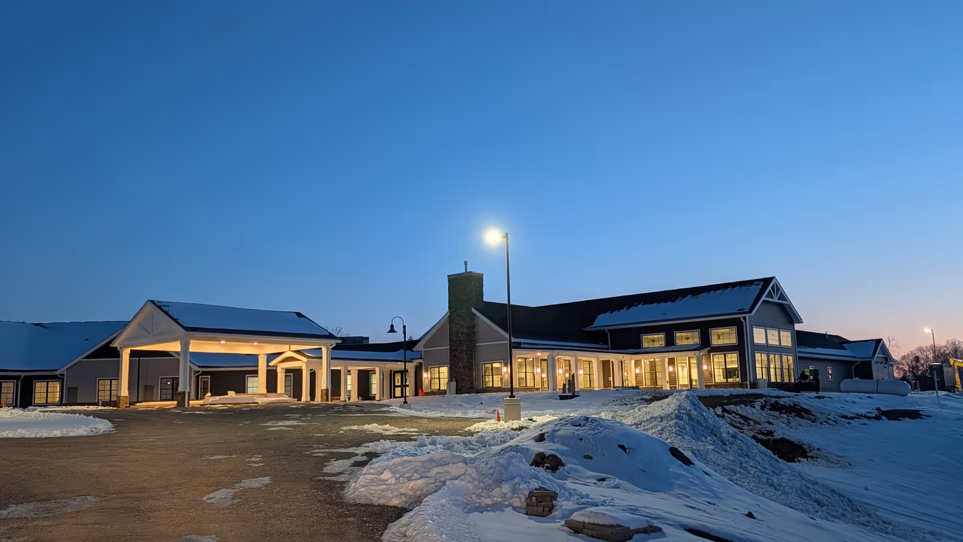 Snow-covered exterior view of Homestead Heights of New Berlin at dusk.