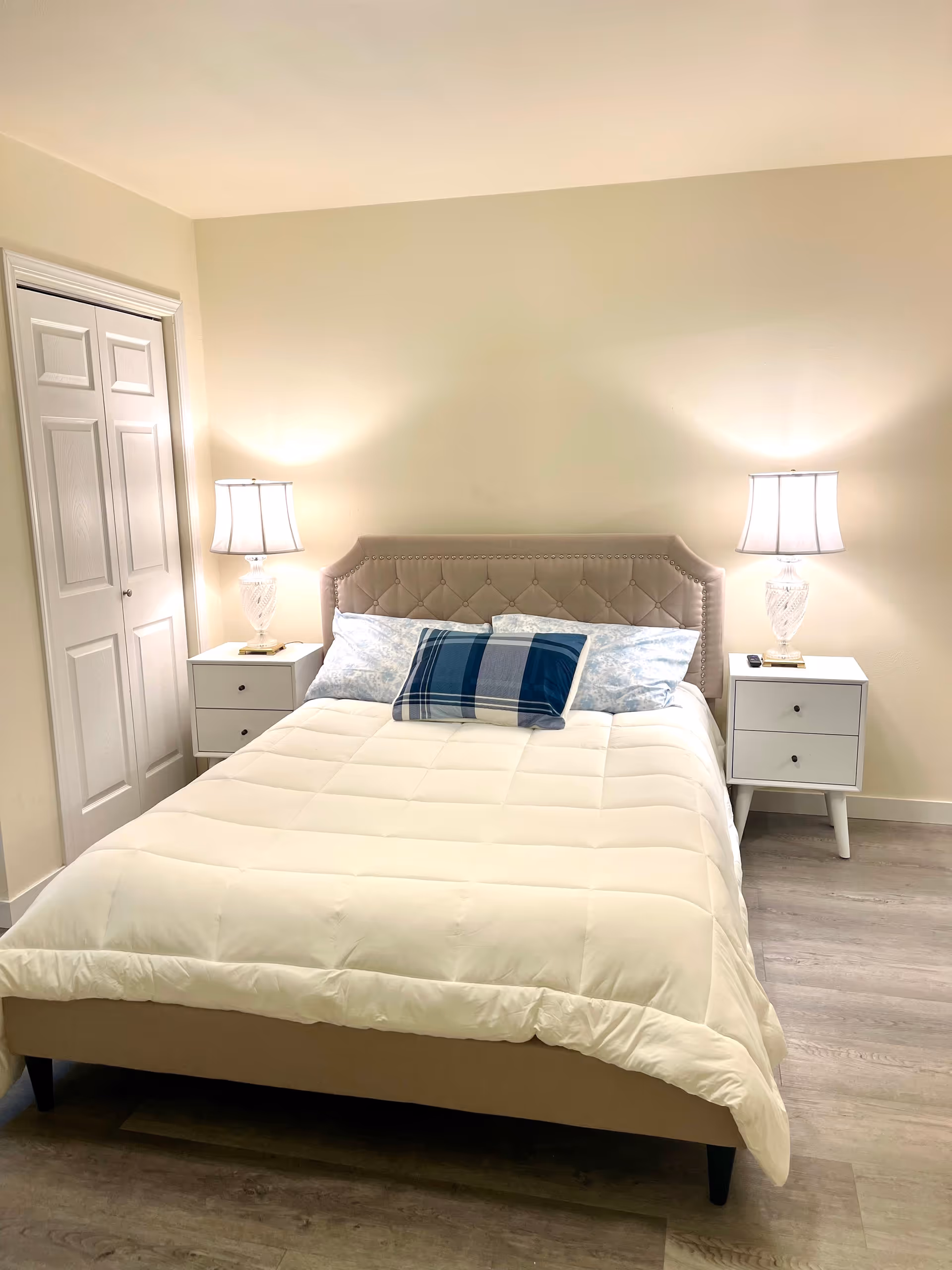 A clean, cozy bedroom with a tufted headboard, two nightstands, and lamps.