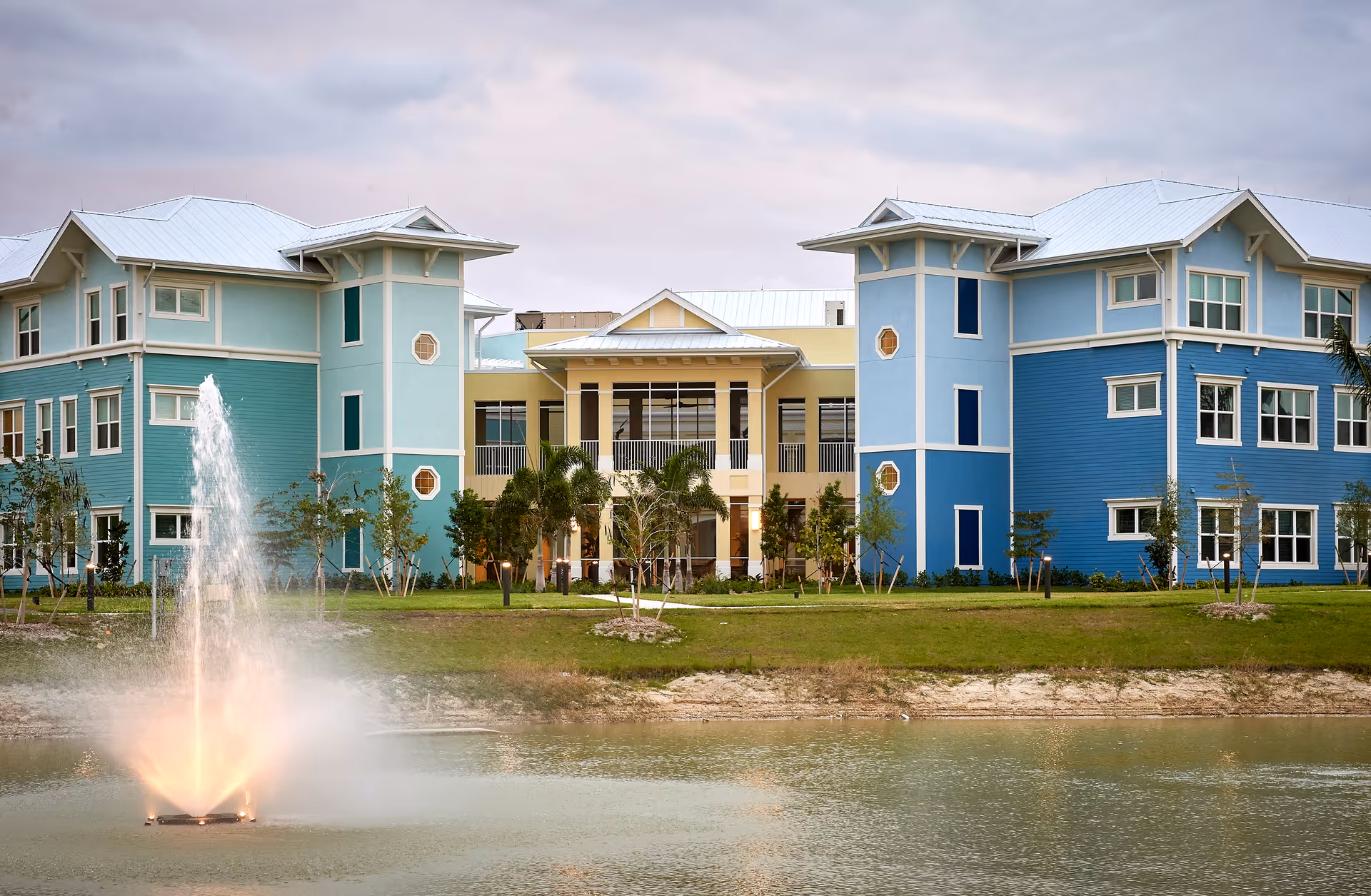 Colorful Palmview at Gulf Coast Village exterior with a central fountain and pond.