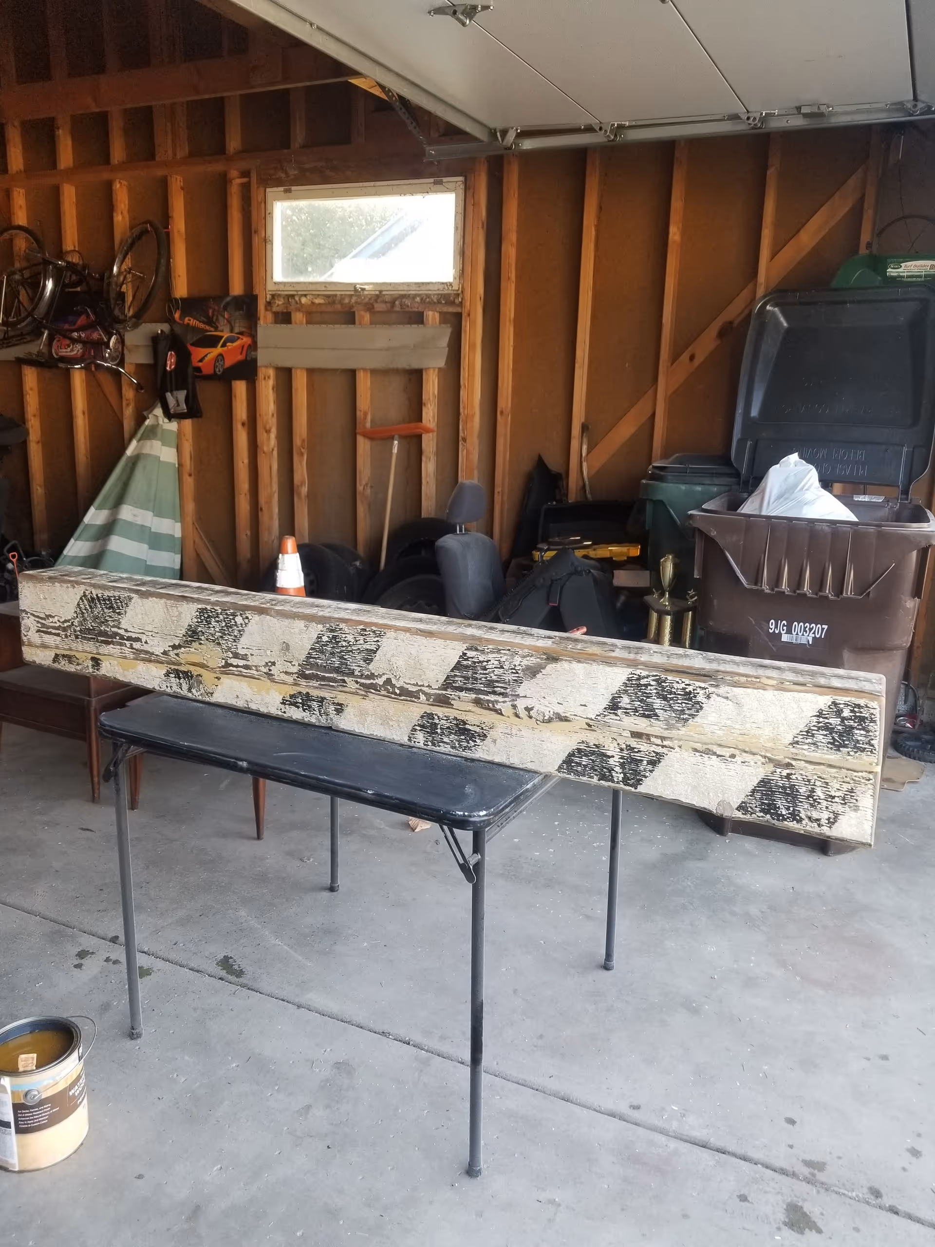 Cluttered garage interior with a long bench, table, bikes, and storage items.