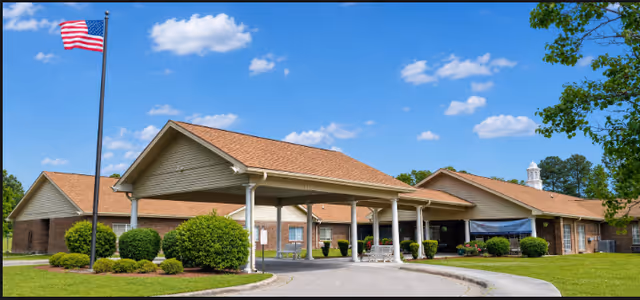 Front view of Croatan Village senior living facility with covered entrance and flagpole.