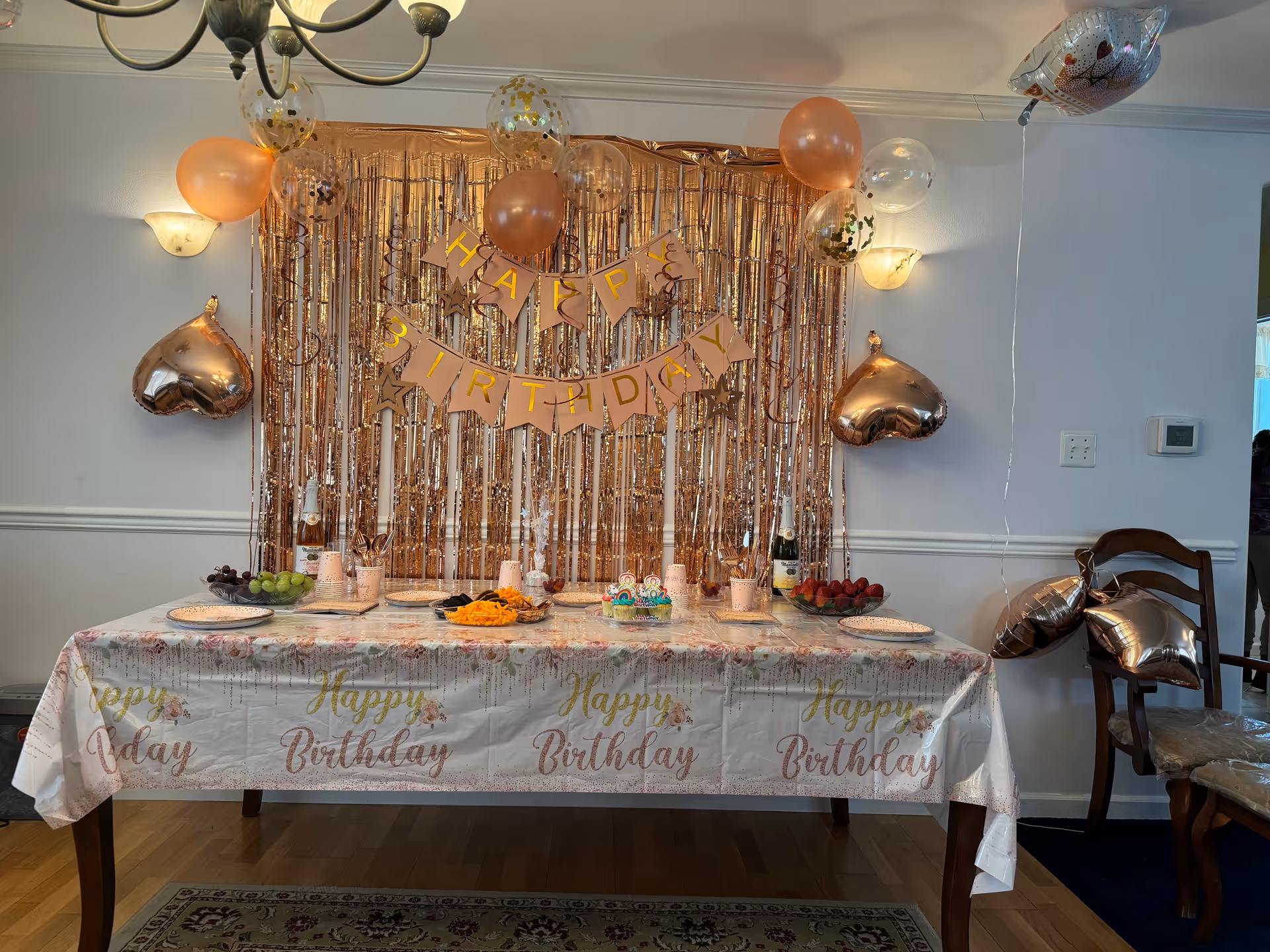 Birthday party setup with balloons, banner, streamers, and cake on a decorated dining table.