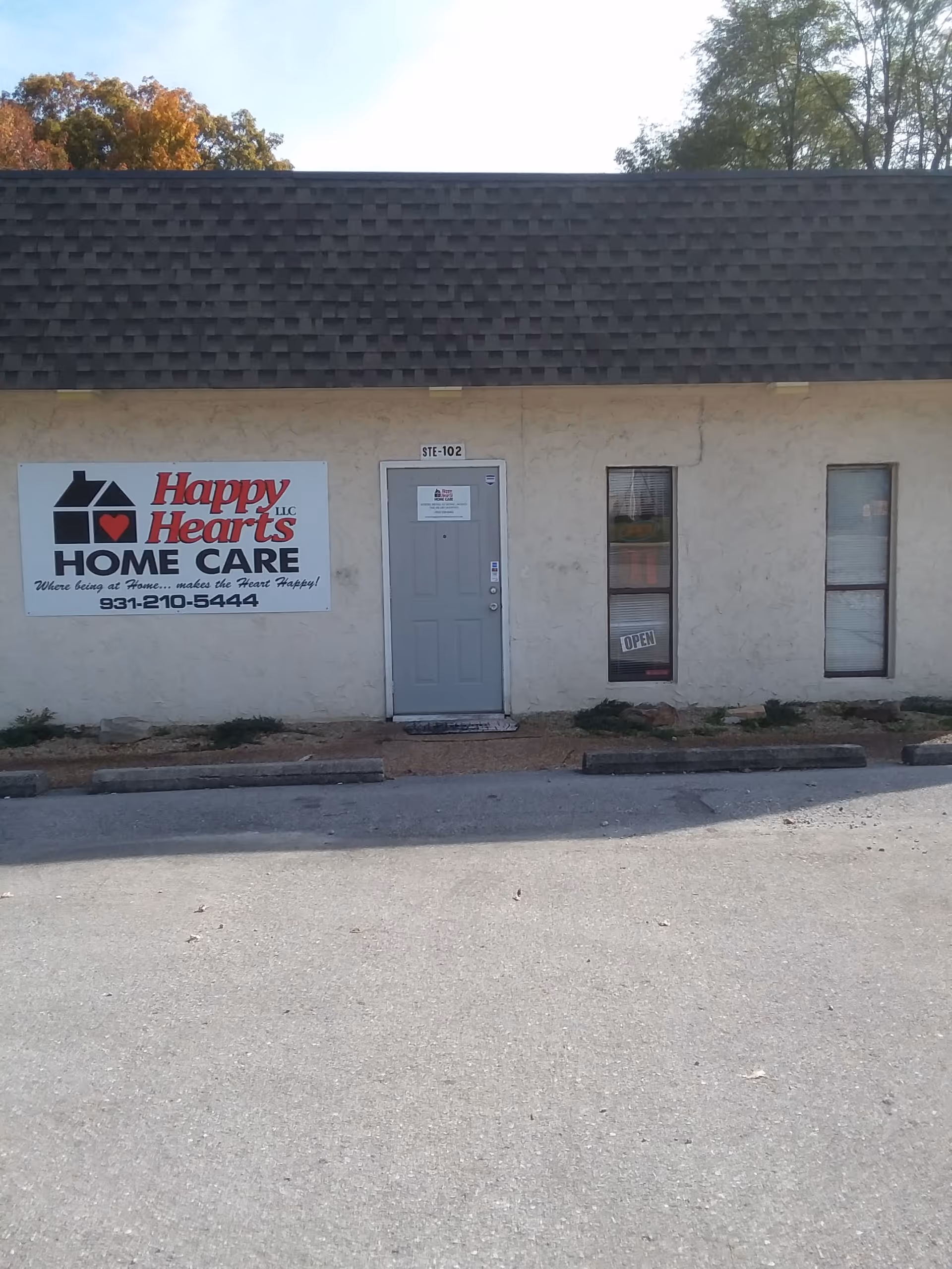 Exterior view of a small facility with Happy Hearts Home Care LLC sign and front door.