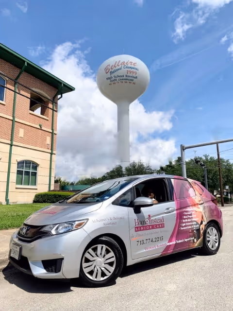Home Instead branded van parked outside a brick building with a water tower behind.