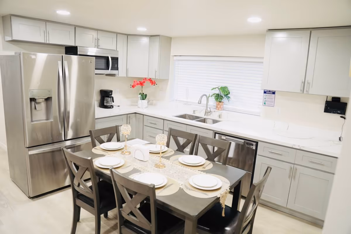 Modern gray kitchen with stainless steel appliances and a dining table set for six.