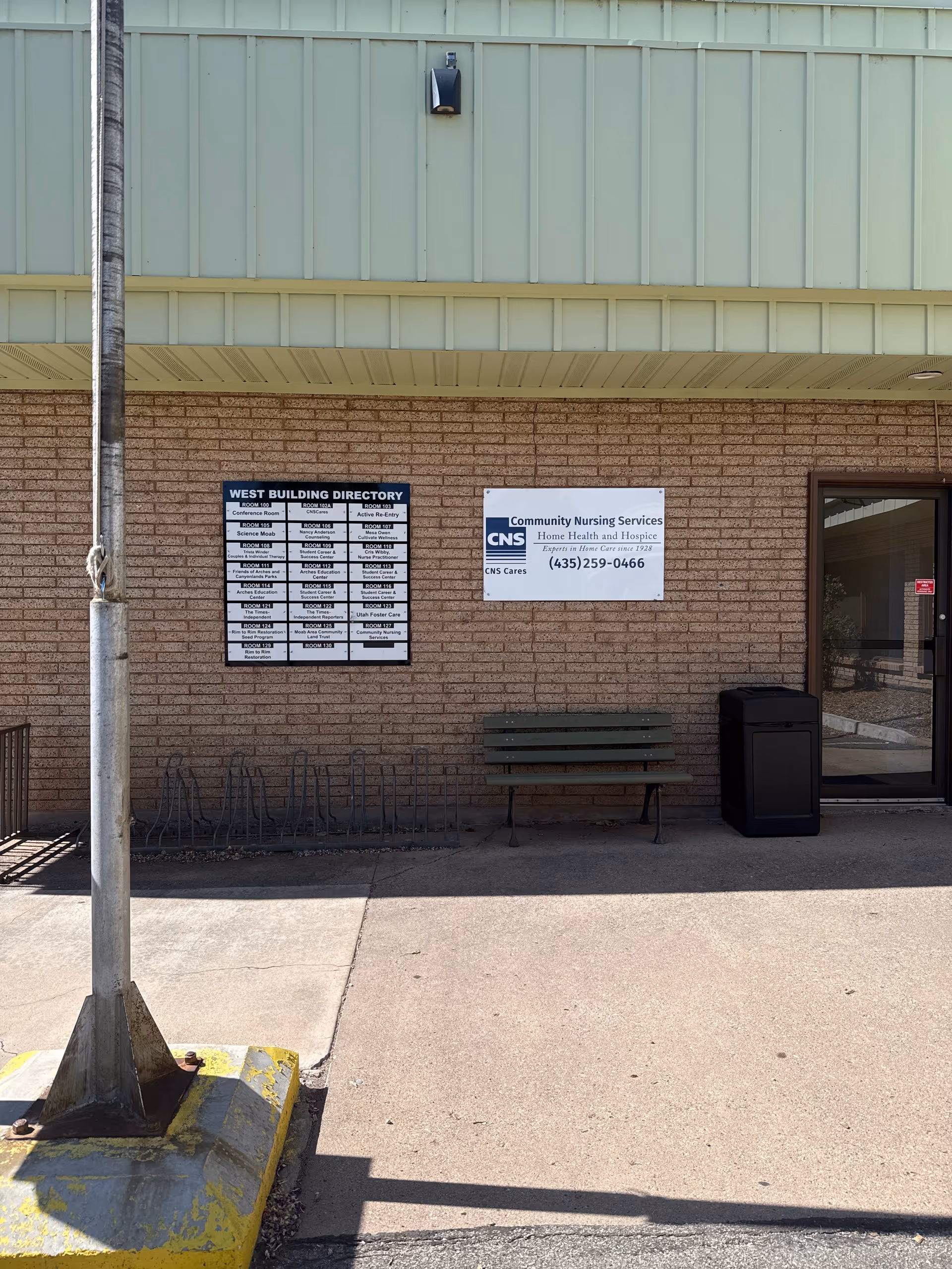 Exterior view of Community Nursing Services Moab building with directory signs and a bench.
