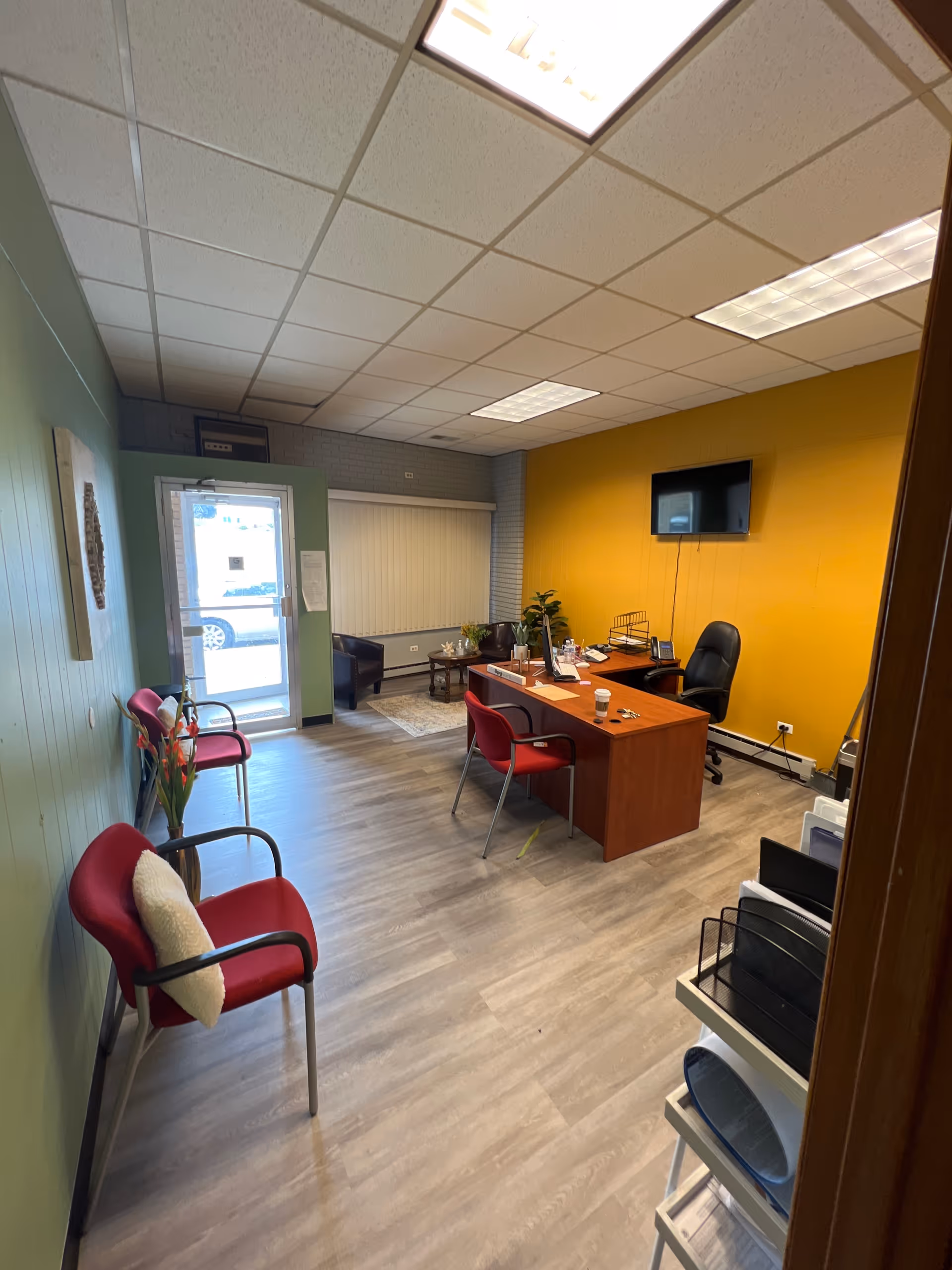 Indoor reception area with desk, chairs, and yellow accent wall in a senior facility.