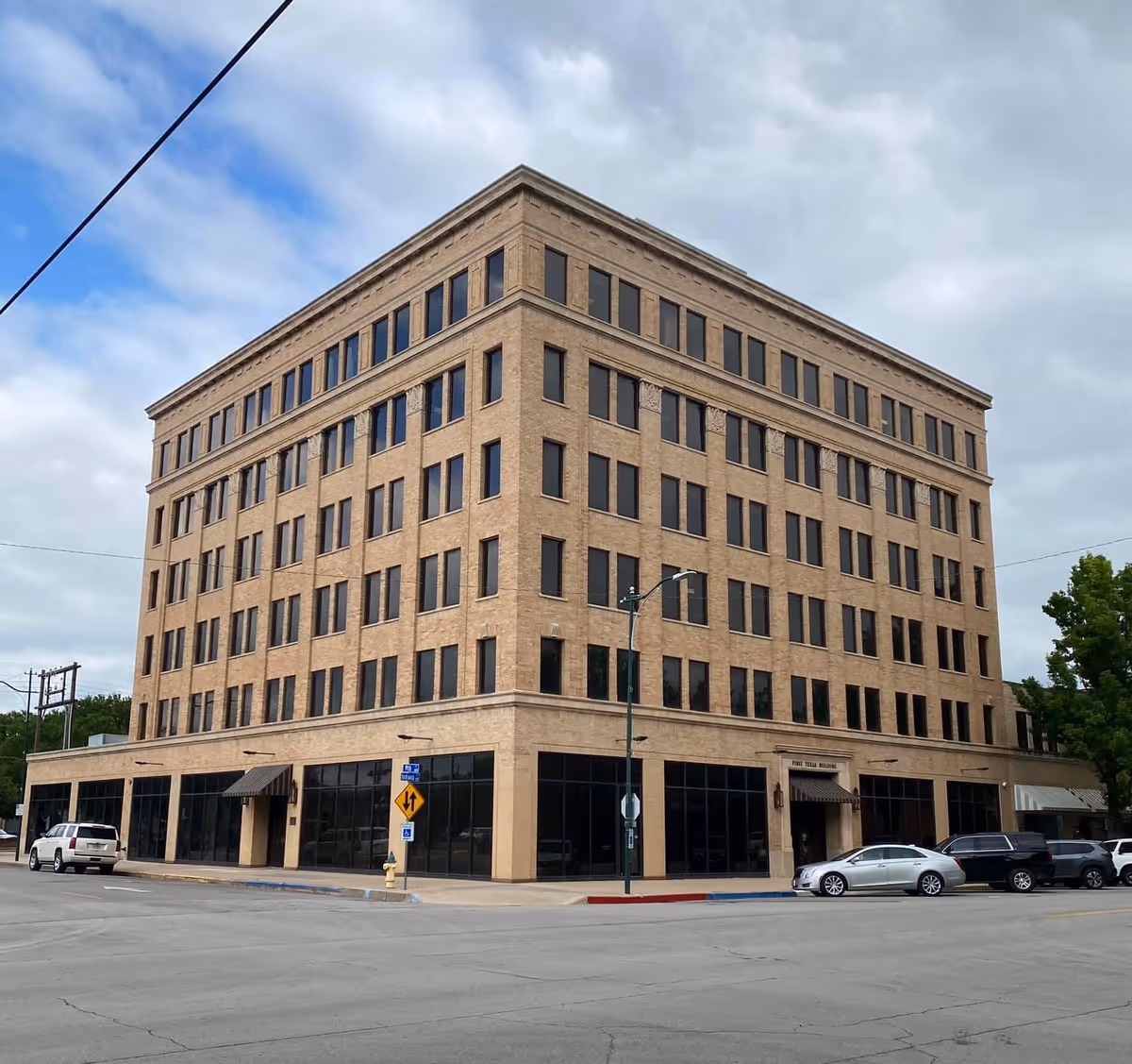 Tall beige brick building with numerous windows along a city street
