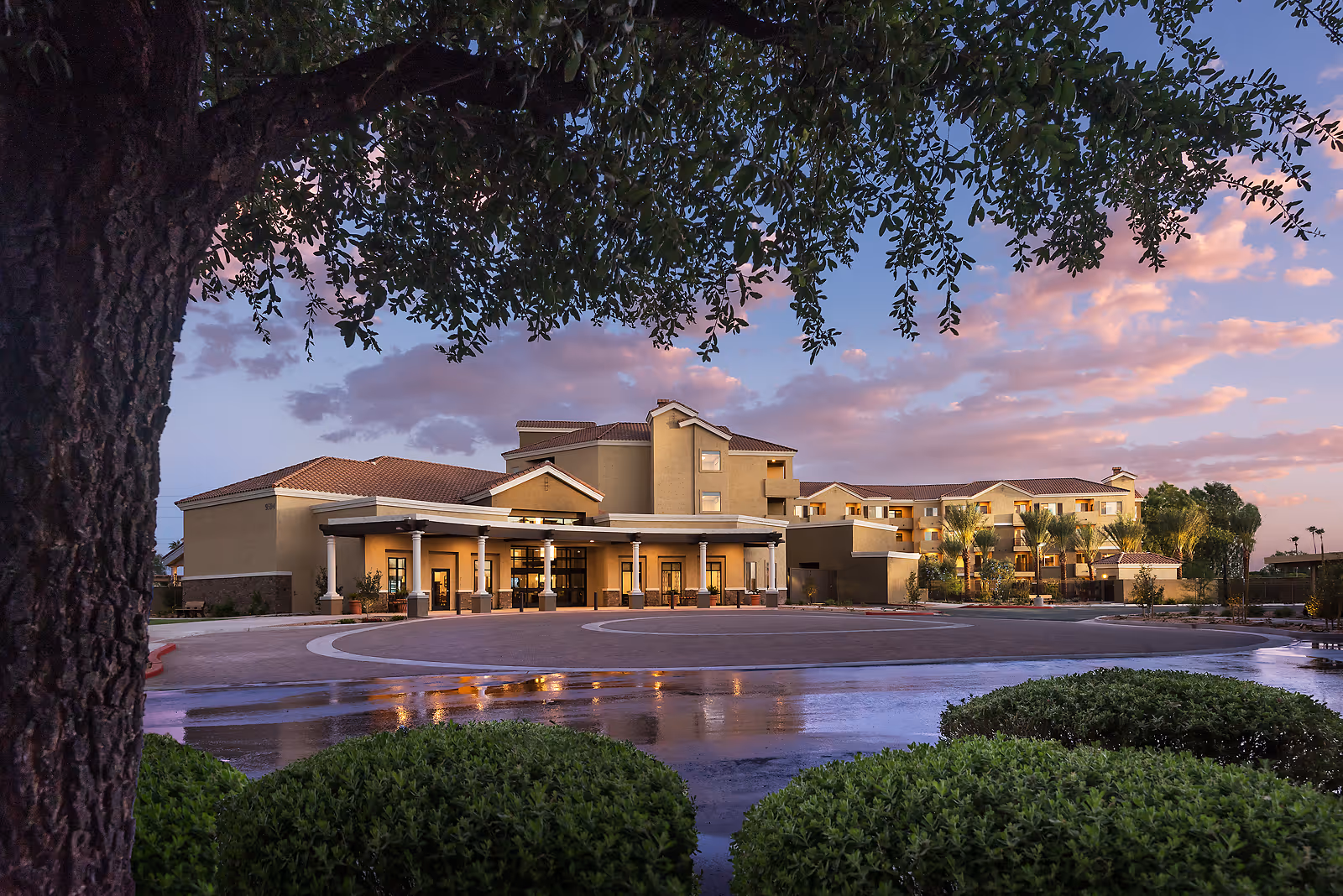 Sunset lit exterior of a Renaissance Luxury Apartment senior living facility with a circular driveway.