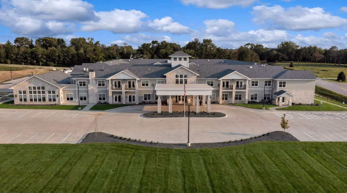A large modern senior living facility viewed from the parking lot with a welcoming entrance.