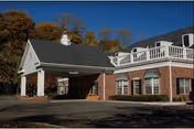 Brick rehabilitation facility with a covered entrance and white railing on a sunny day.