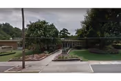 Exterior view of Carlyle Senior Care of Aiken showing entrance with landscaping and green lawn.