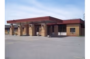 Front view of a brick nursing center with a red canopy and empty parking.