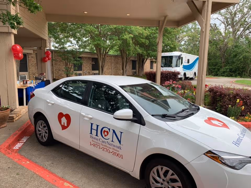 White HomeCare Network car parked at facility entrance with balloons