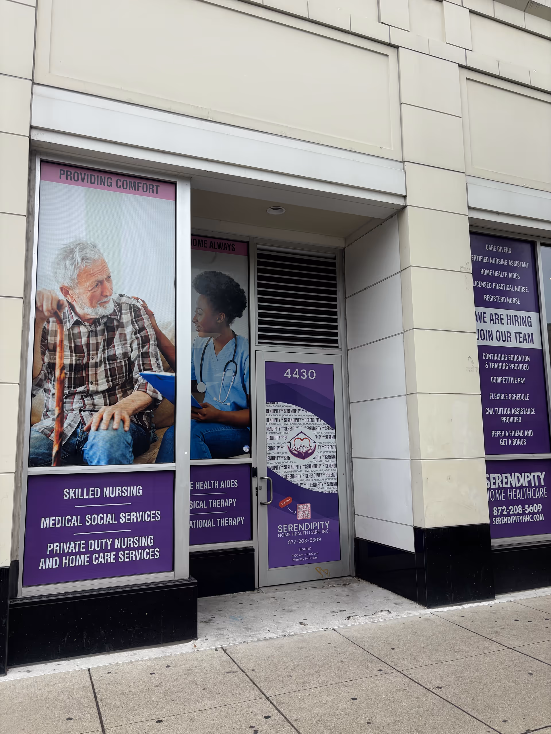 Exterior storefront of Serendipity Home Healthcare with purple signs and posters advertising services.