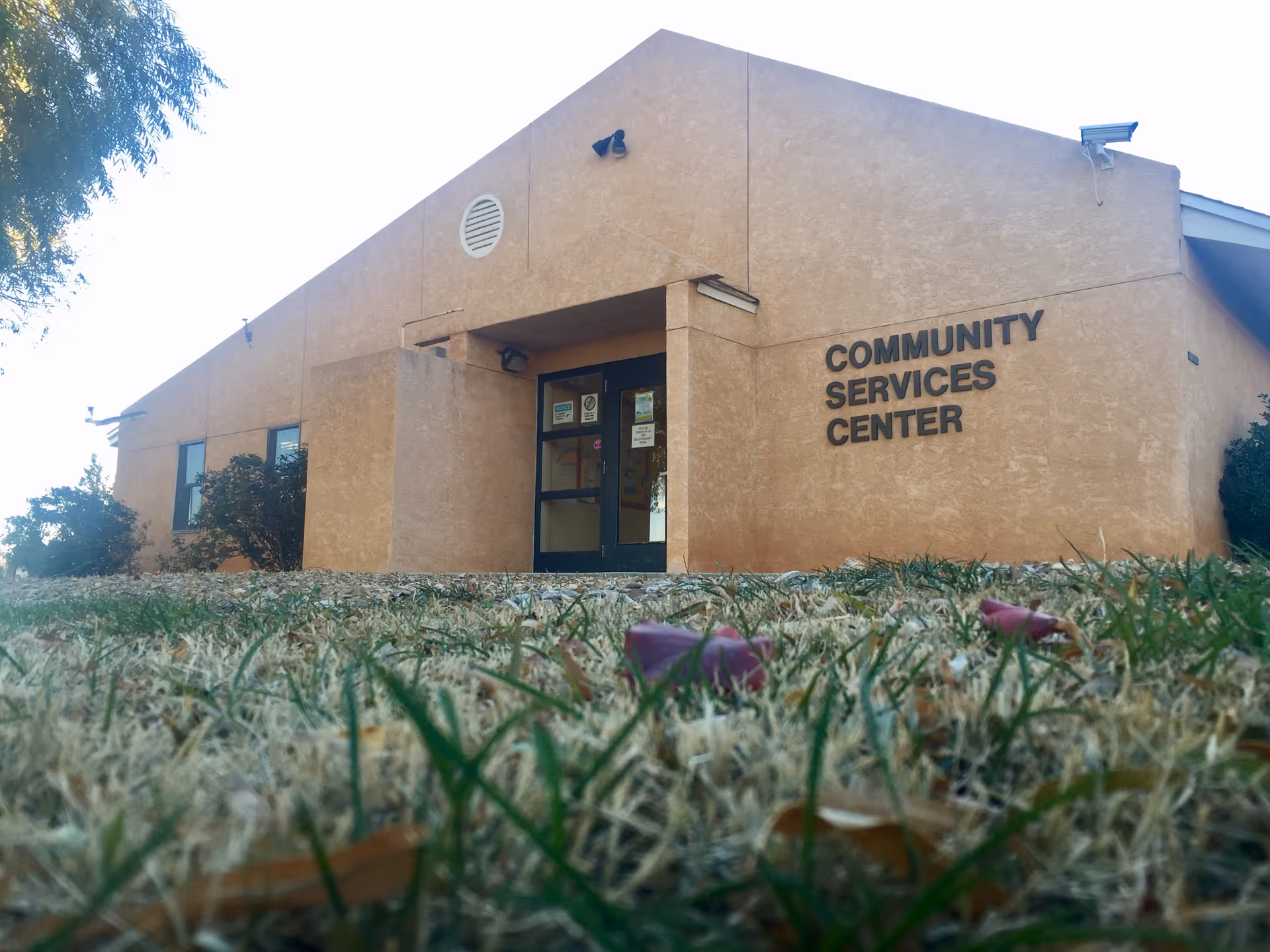 Beige Community Services Center exterior with front entrance and surrounding grass.