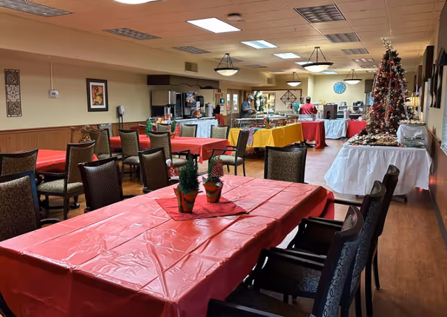 Banquet-style dining room with colorful tablecloths and a decorated Christmas tree.
