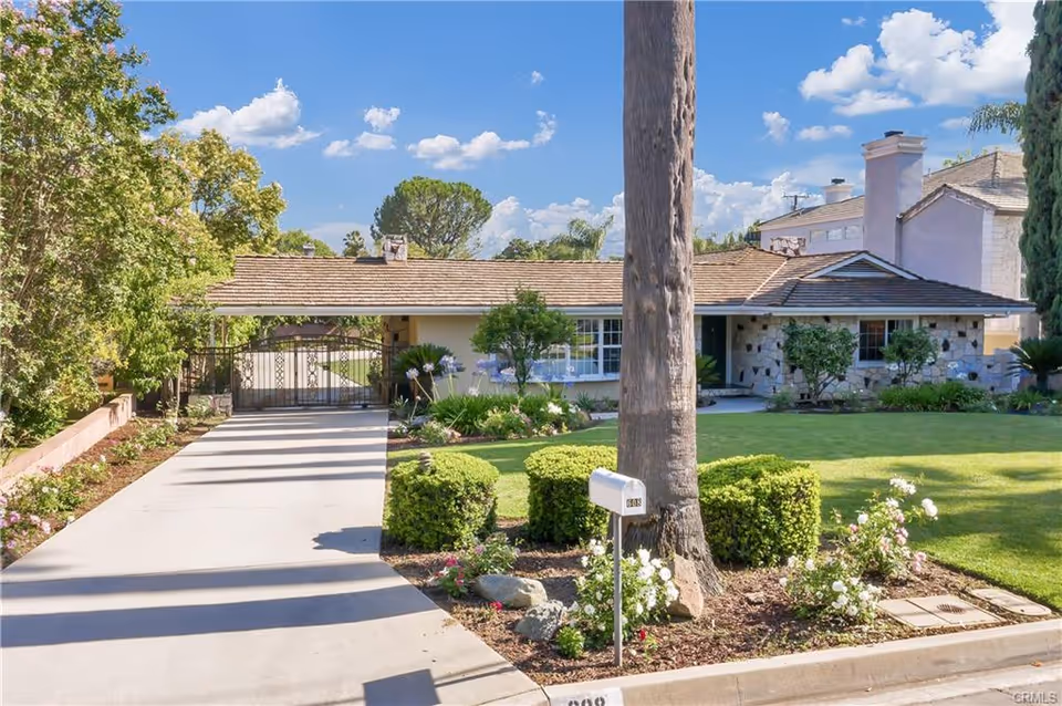 Front view of a single-story assisted living home with manicured lawn and gated driveway.