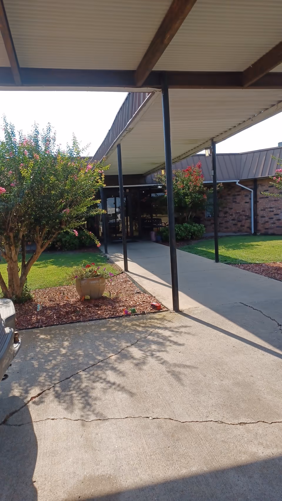 Exterior view of a covered walkway leading to the entrance of a brick senior center.