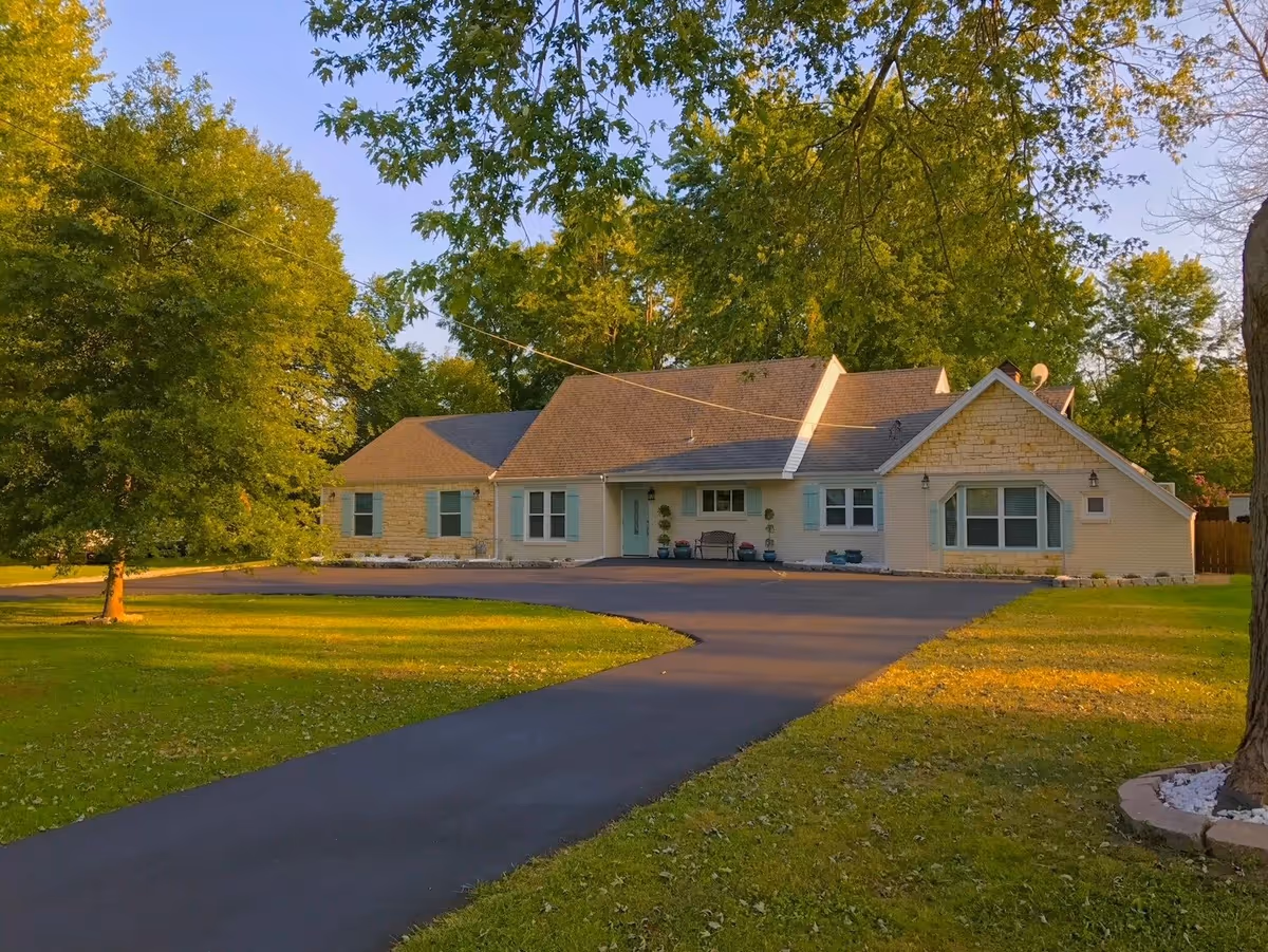 Front view of a single-story assisted living facility with curved driveway and trees.