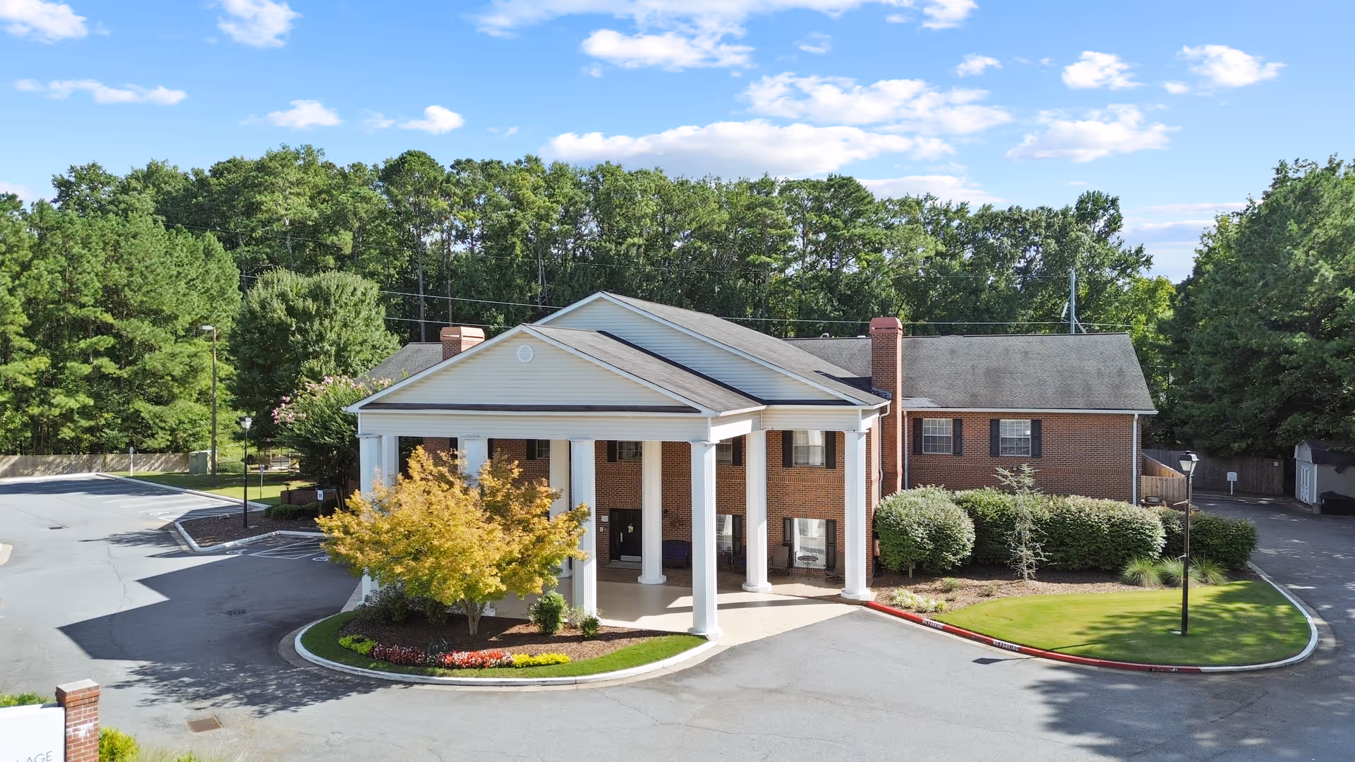 Front entrance of a brick senior living facility with a porte-cochere and landscaping.
