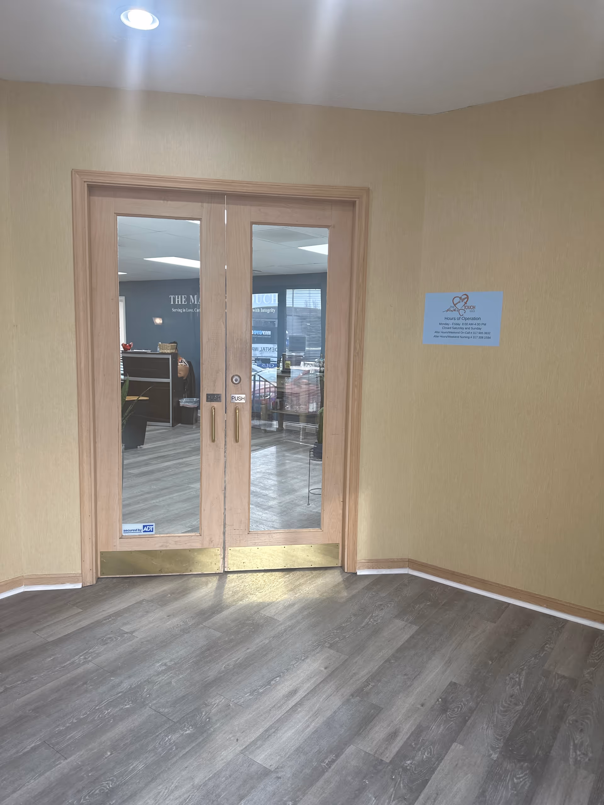 Double wooden glass doors open to a lobby and reception area inside.