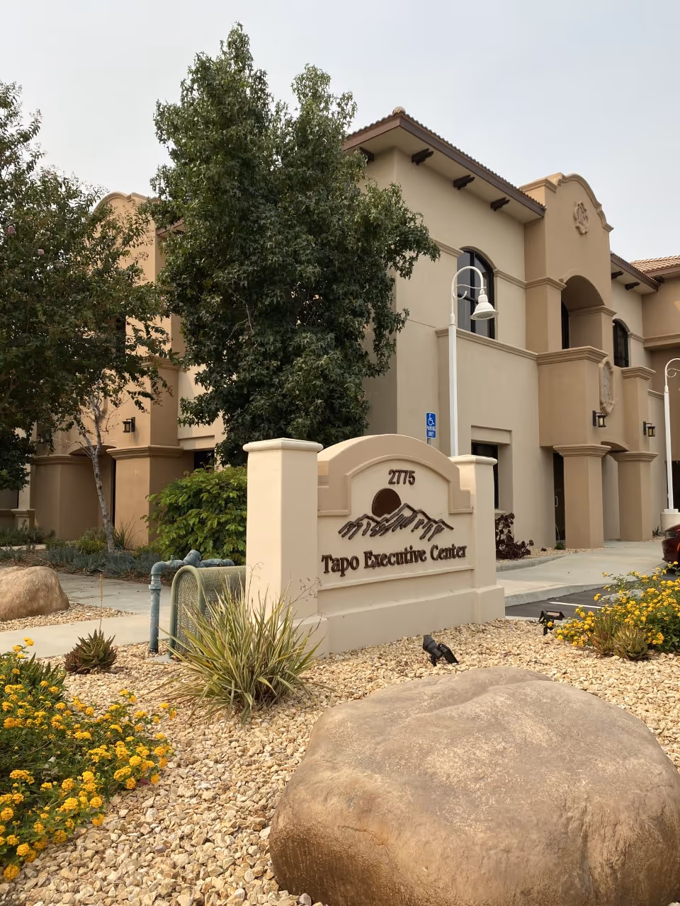 Exterior view of Tapo Executive Center senior living building with desert landscaping and signage.