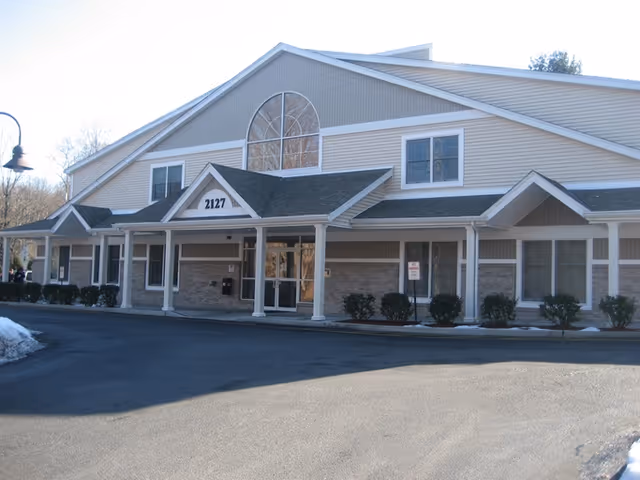 Exterior of a senior living facility with a covered entrance and arched window.