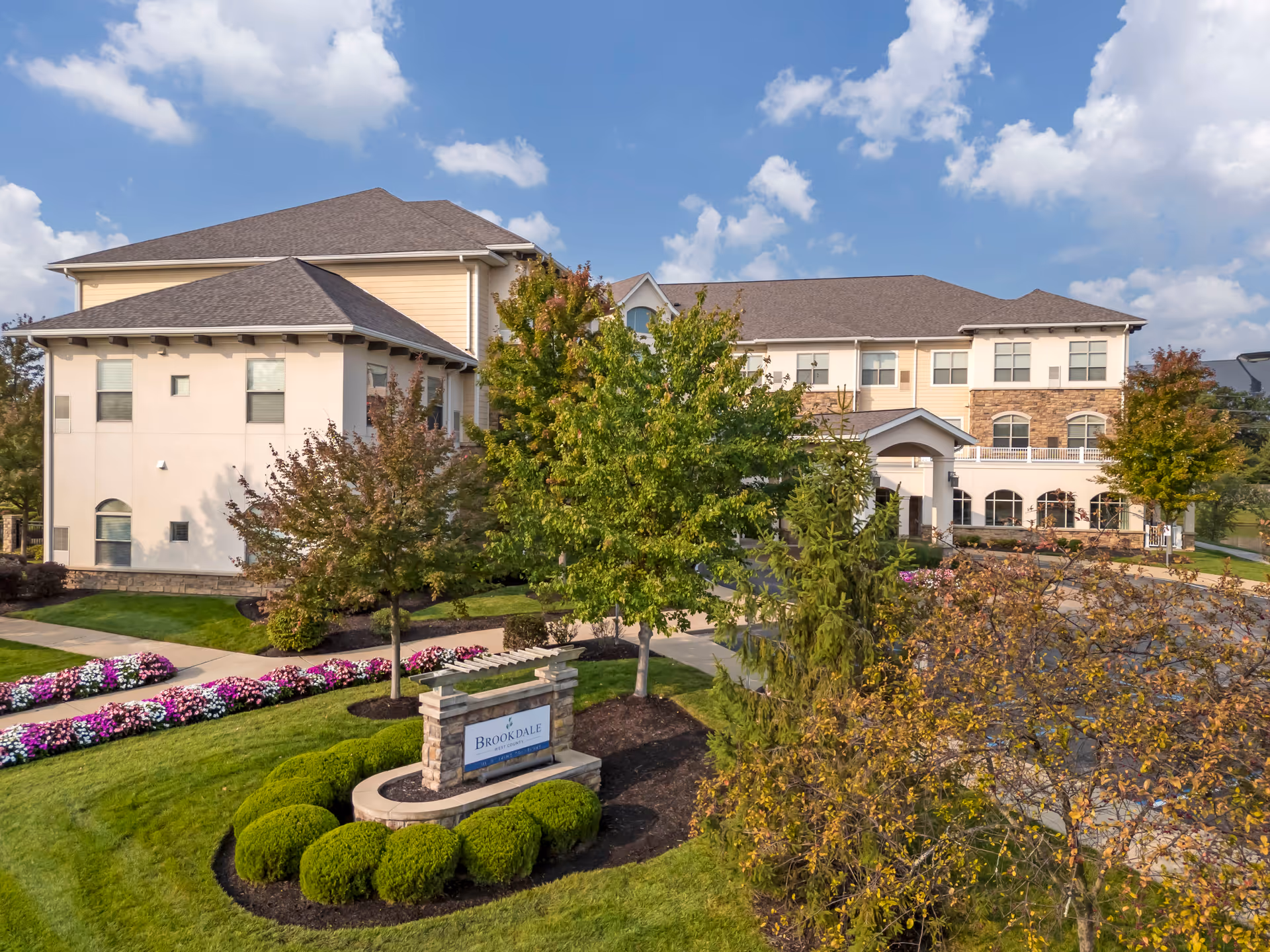 Exterior view of Brookdale West County with landscaped grounds and a beige multi-story building.