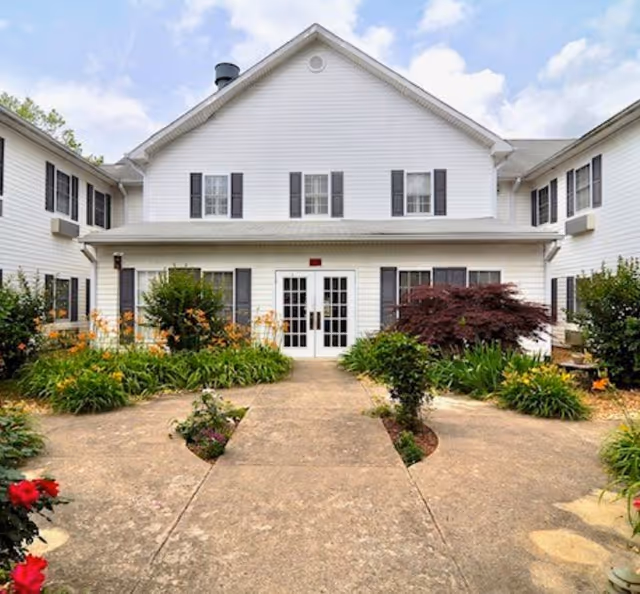 Front exterior of Regency House senior living facility with entry doors and landscaped path.