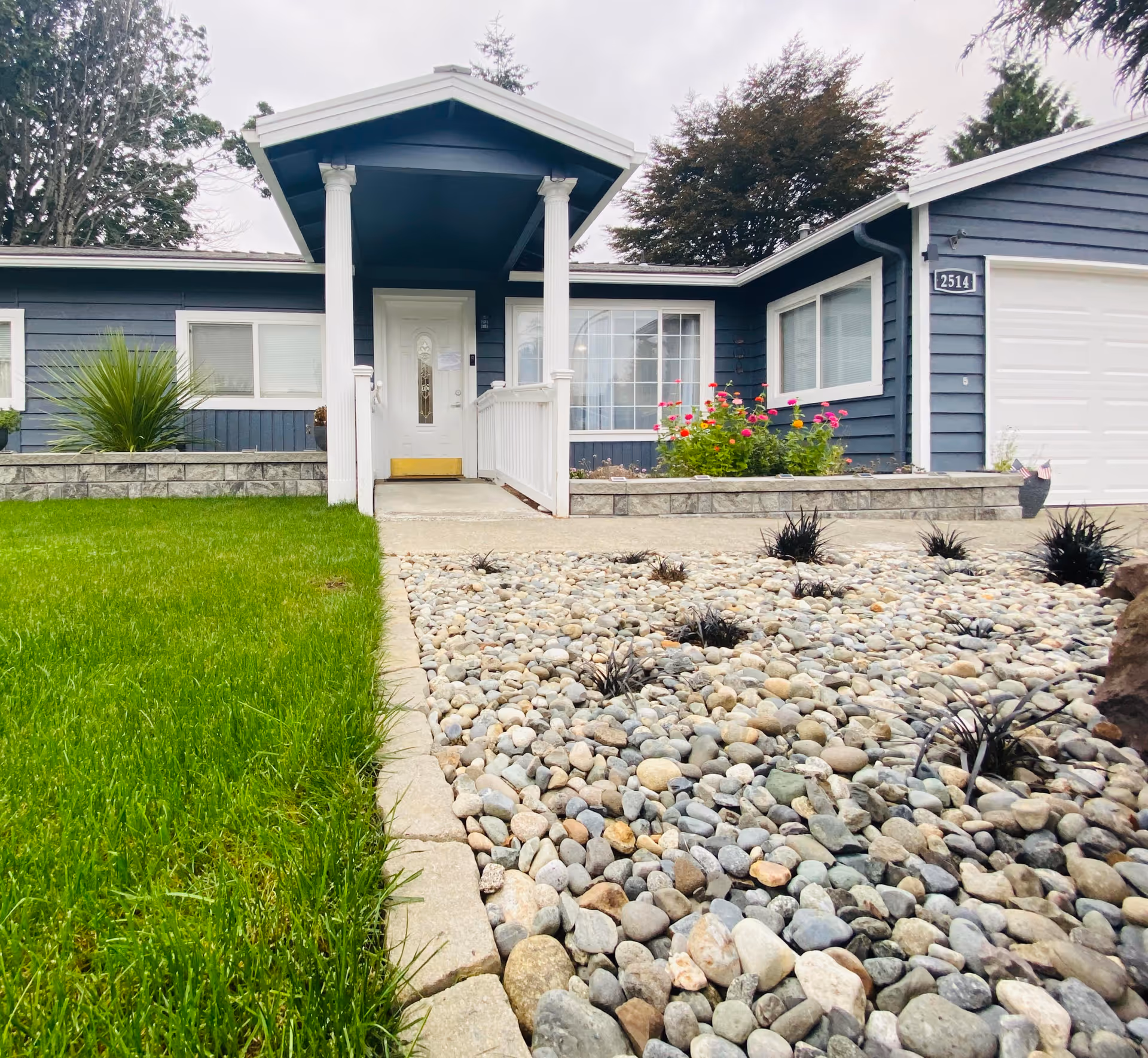 Blue single-story senior living facility exterior with front entry and rock landscaping