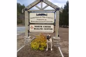 Outdoor sign for Elderwood at North Creek with a small dog nearby.