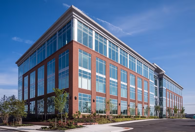 Modern brick nursing facility exterior with large glass windows and tidy landscaping.