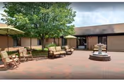 Outdoor brick patio with seating, a fountain, and trees.