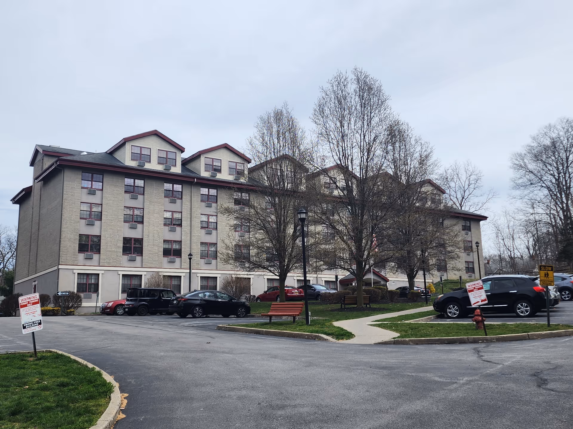Exterior view of Heritage Pointe Apartments with parked cars and trees.